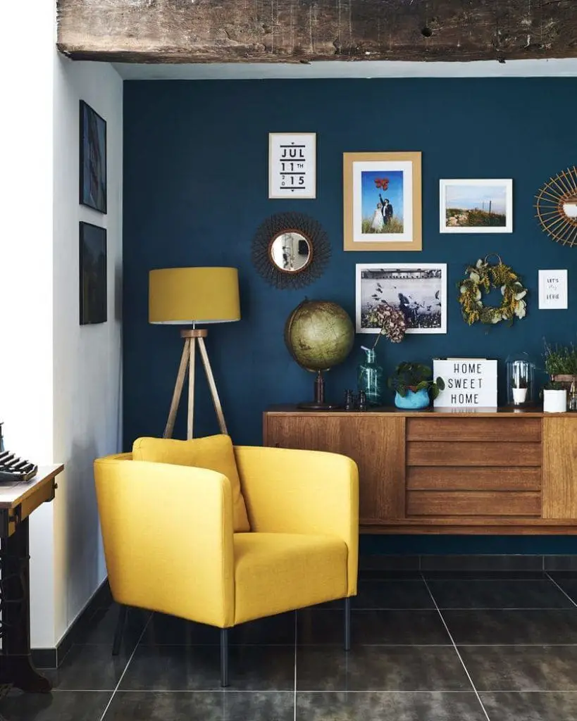 Association de fauteuil jaune avec un mur bleu pétrole dans un salon chic