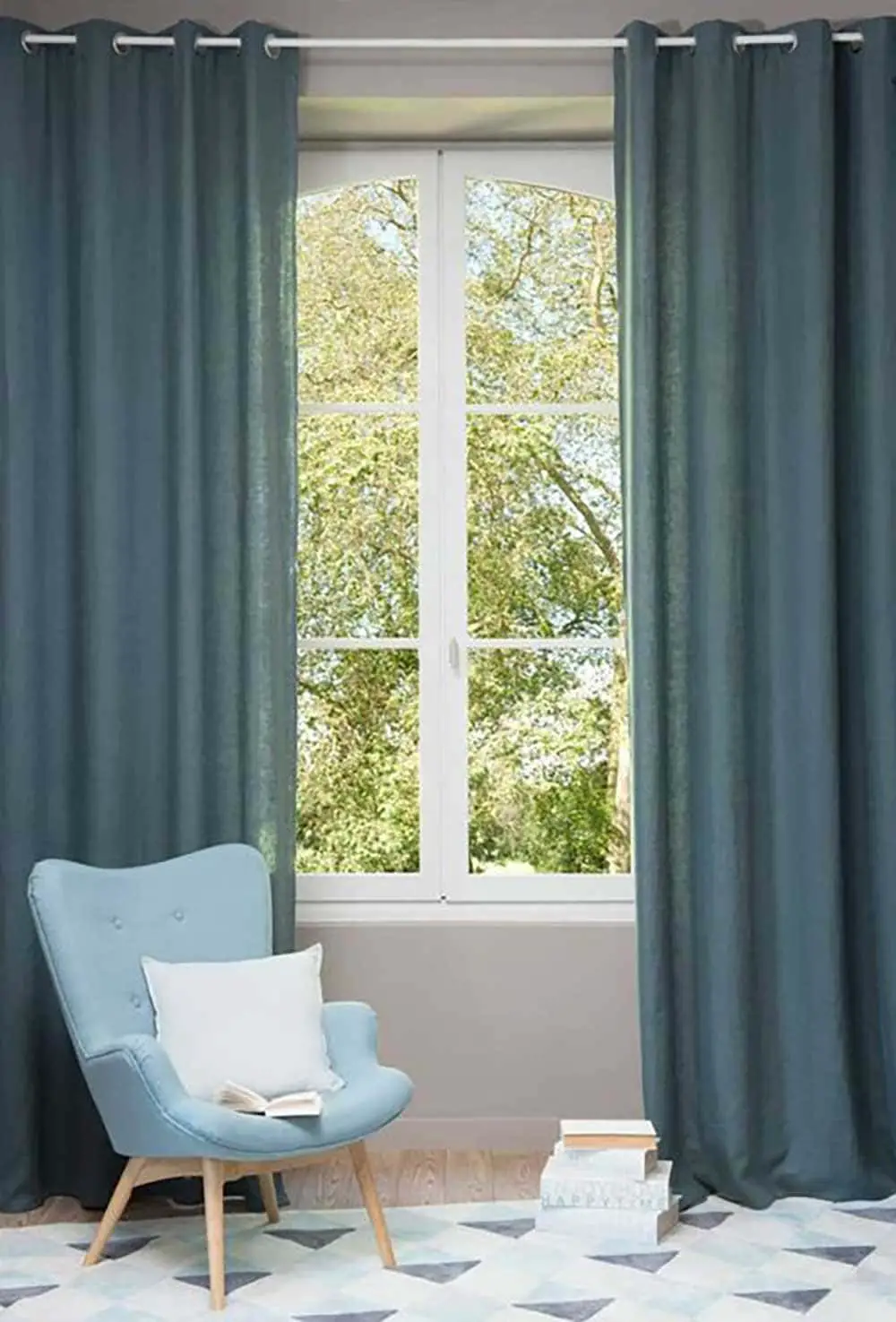 rideaux de couleur bleu pétrole dans pièce cosy avec fauteuil scandinave
