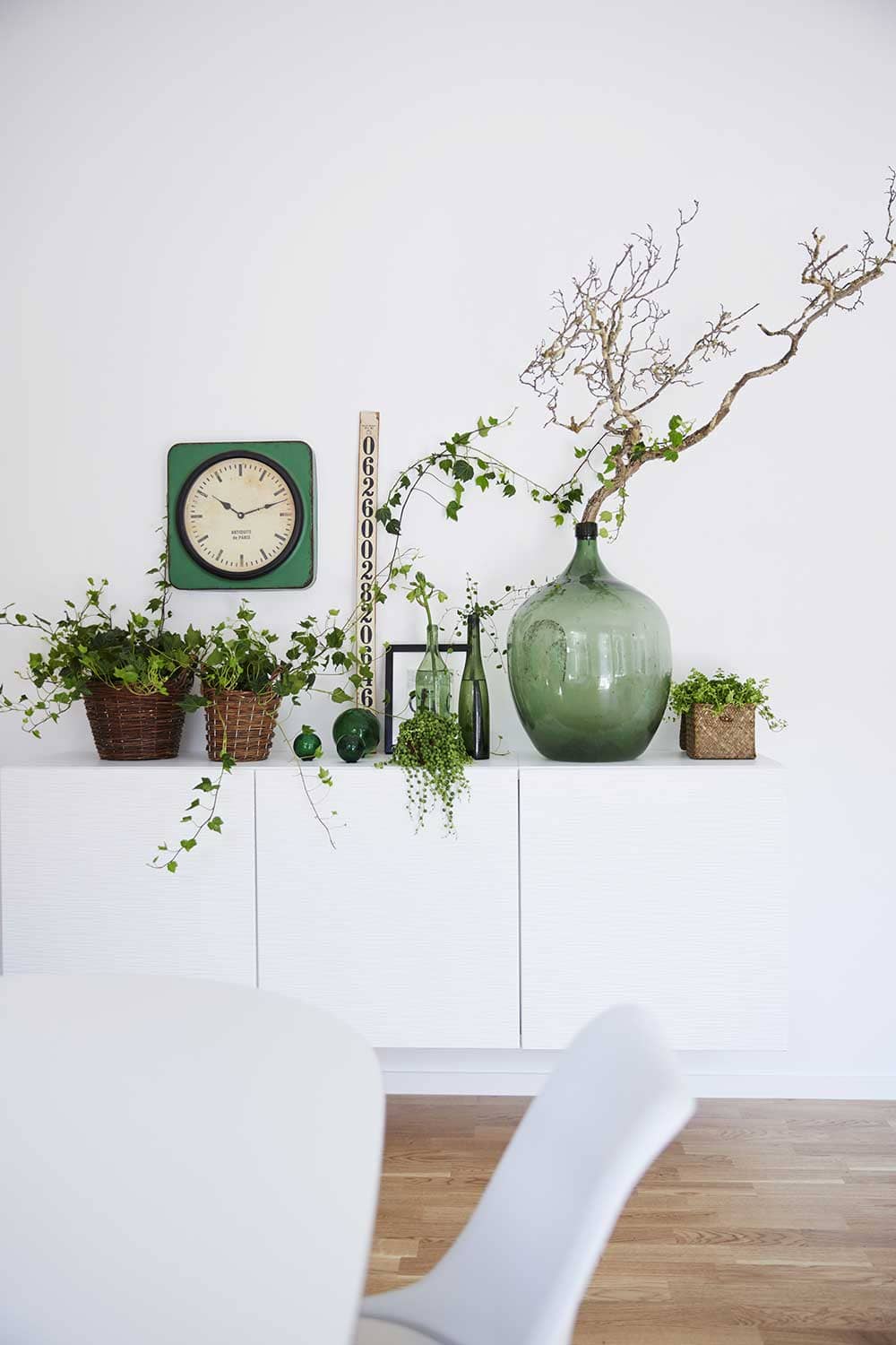 Composition végétale avec bouteilles et jarres en verre sur fond blanc - Decorazine.fr