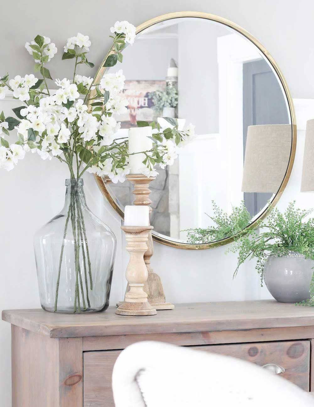 Belle jarre en verre qui décore une petite console bois avec des fleurs blanches - Decorazine.fr